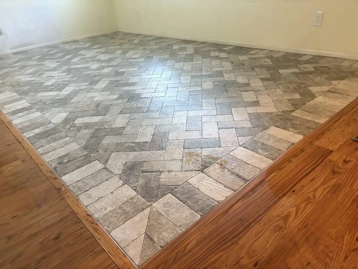 Brick-look porcelain laid in a herringbone field with a mitered border meeting existing wood flooring, Valrico FL