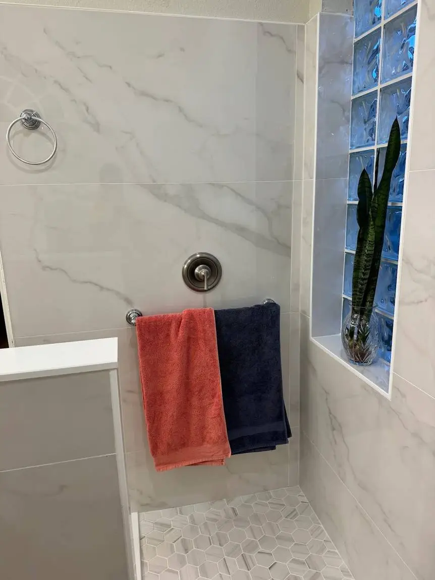 Marble-look porcelain shower wall beside original glass block window in a Brandon FL master bathroom