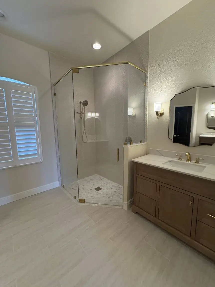 Neo-angle frameless glass shower with textured herringbone wall tile in a Valrico FL master bathroom