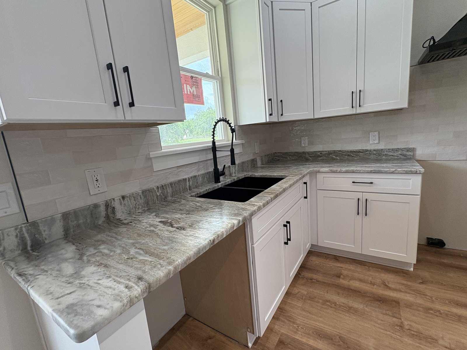Stacked stone-look tile kitchen backsplash with white shaker cabinets in a new Plant City home