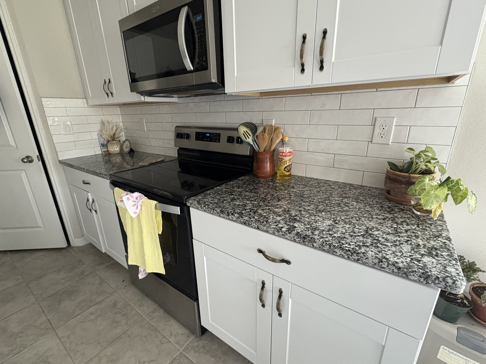 Glossy white subway tile backsplash in an occupied Plant City kitchen with white shaker cabinets and granite countertops