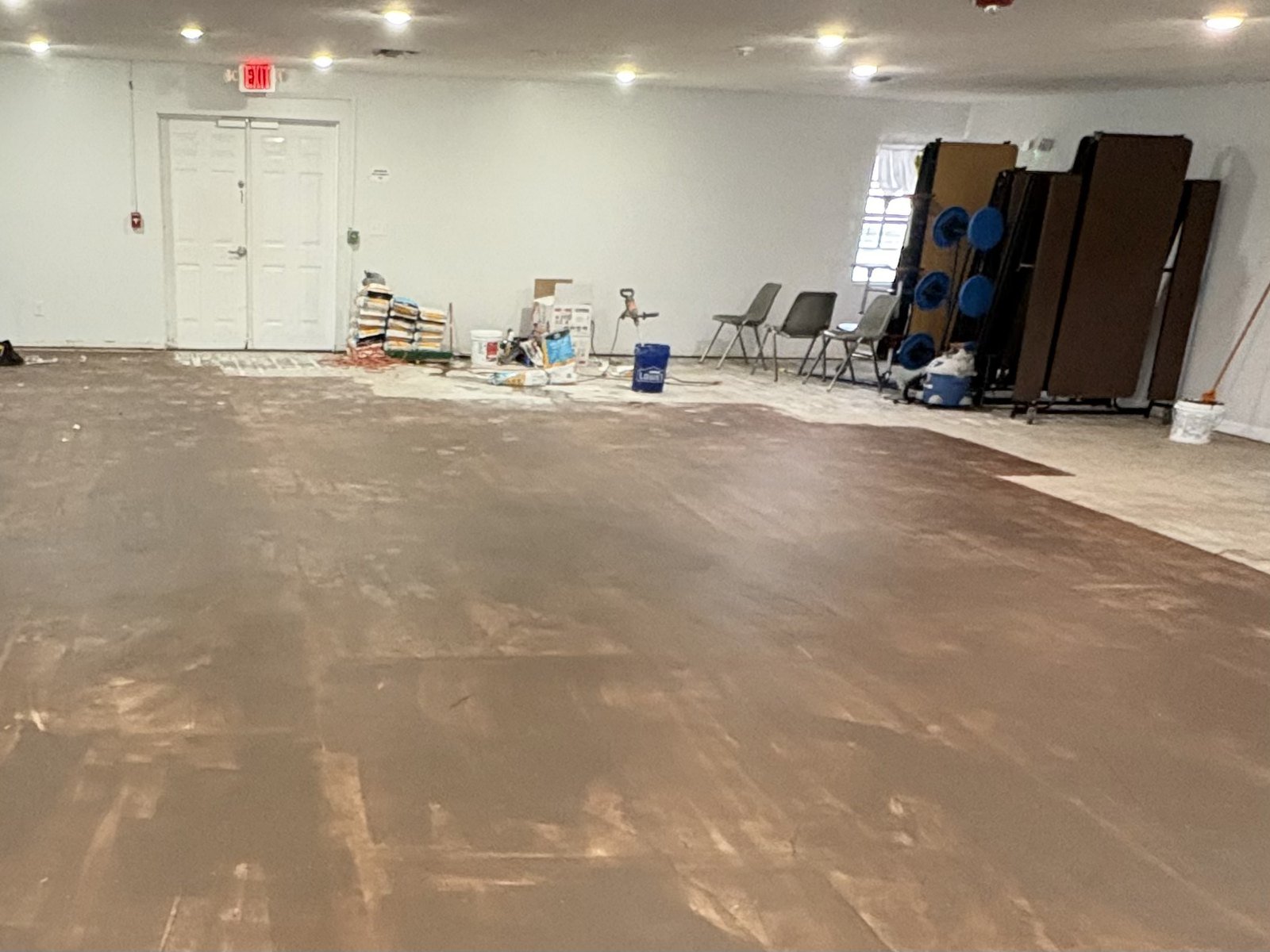 Prepped concrete slab and staged flooring materials in a Plant City church hall